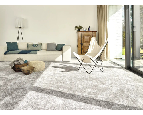 Heller Wohnraum mit Teppichboden, Sofa, Sessel und Holzelementen für ein freundliches Ambiente