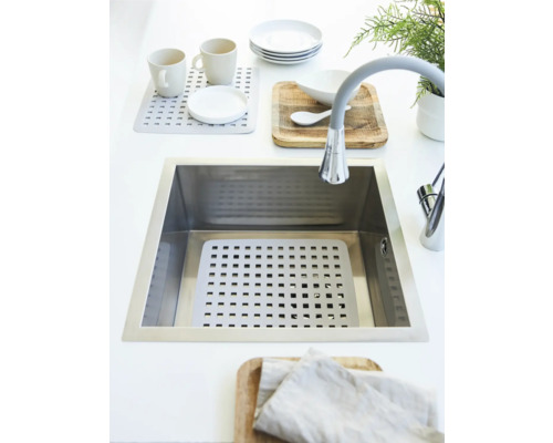 Spüle mit Abtropfmatte, Geschirr und Armatur auf einer Küchentheke.