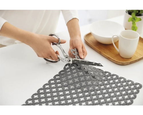 Zuschneidbare Schubladenmatte wird mit einer Schere zugeschnitten.