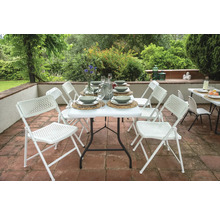 Gedeckter Gartentisch mit weißen Klappstühlen auf einer Terrasse.