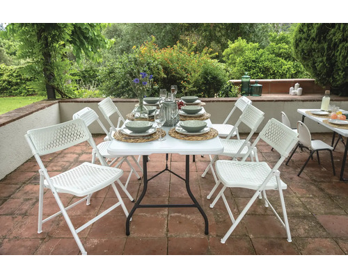 Gedeckter Gartentisch mit weißen Klappstühlen auf einer Terrasse.