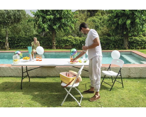 Szene im Garten mit Stehtisch, Kühlbox und Klappstühlen neben einem Pool.