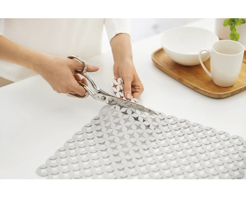 Zuschneiden einer rutschfesten Matte mit einer Schere auf einem Tisch