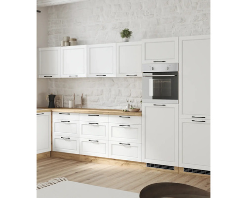 Cuisine claire avec armoires blanches, plan de travail en bois et four intégré.