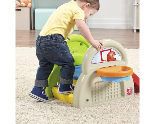 Bambin grimpant sur une aire de jeux avec un panier de basket