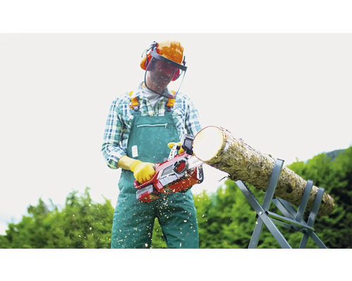 Un homme scie une bûche avec une tronçonneuse sur un chevalet de sciage. Il porte des vêtements de protection.