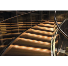 Gewendelte Holztreppe mit Glasgeländer und integrierter Beleuchtung