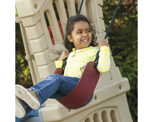 Un enfant souriant se balance sur une balançoire dans le jardin.