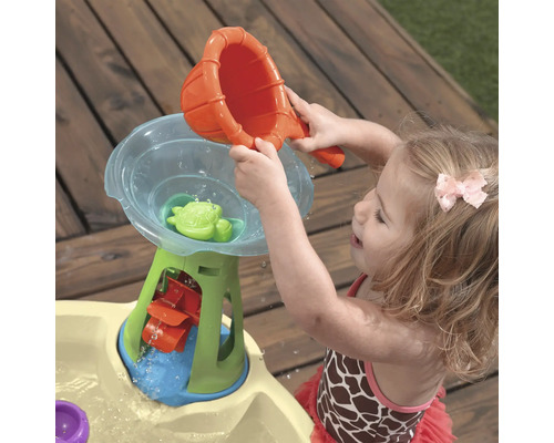Fille jouant avec une table d''eau d''extérieur avec entonnoir, roue à eau et tortue