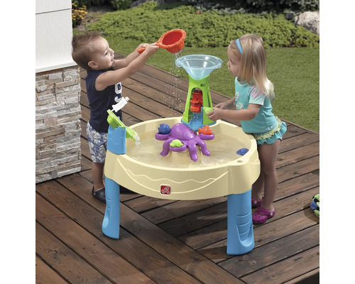 Des enfants jouent avec une table d''eau Step2 à l''extérieur avec une roue à eau et une pieuvre