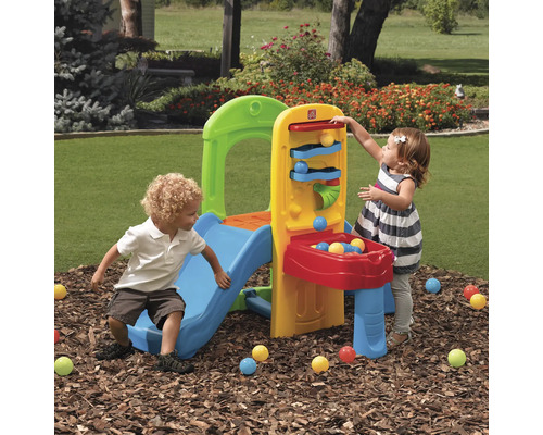 Des enfants jouent avec une structure d''escalade Step2 avec toboggan et rampe à balles dans le jardin.