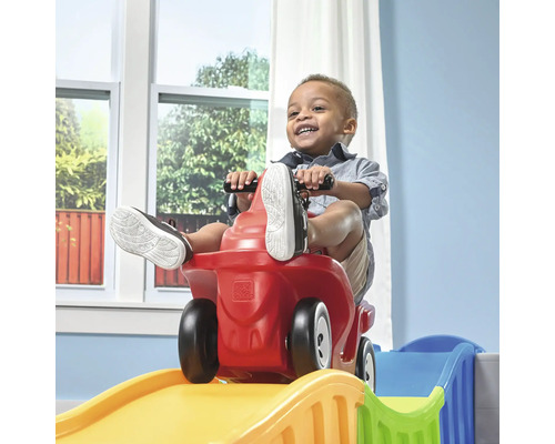 Enfant sur une voiture Step2 rouge dévalant une piste jaune et bleue