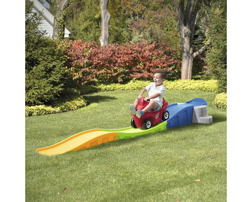 Enfant sur une voiture jouet rouge avec une piste dans le jardin