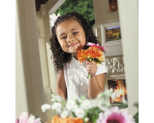 Une fille avec un bouquet de fleurs dans une cabane de jeu.
