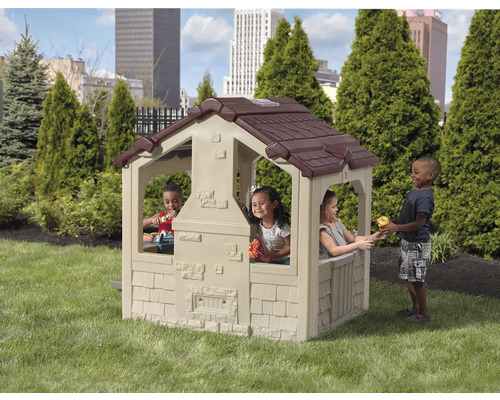 Maisonnette pour enfants avec toit brun et enfants jouant dans le jardin.