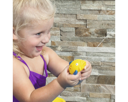 Fille avec un pistolet à eau en forme de poisson dans le jardin