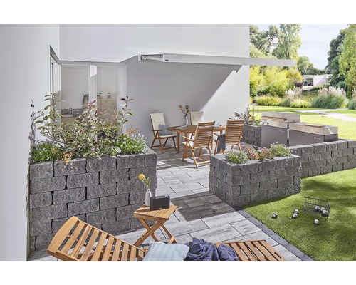 Terrasse avec mobilier de jardin, barbecue et parterres surélevés en pierre