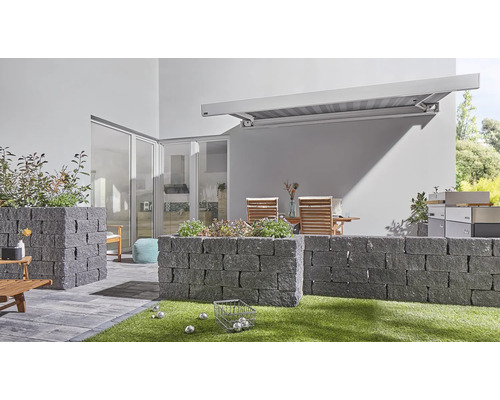 Espace extérieur avec murs en pierre, store, mobilier de jardin et boules de pétanque sur pelouse