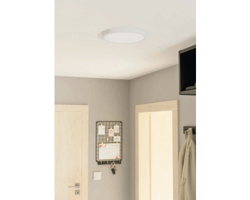 Deckenleuchte in einem Raum mit einer Tür, einem Memoboard und einer Garderobe