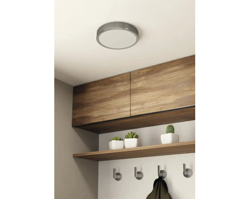 Deckenleuchte in einem hellen Raum mit Holzschränken, Regal und Hakenleiste.