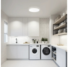 Buanderie lumineuse avec machines à laver, lavabo, armoires et étagères pour l''entretien du linge