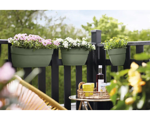 Scène de balcon avec des jardinières sur une balustrade, plantées de fleurs roses, blanches et jaunes, avec une table et des chaises au premier plan