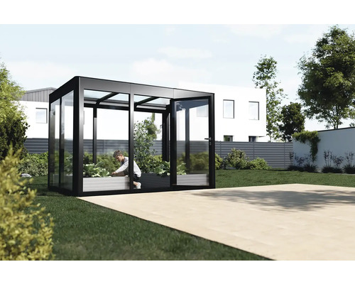 Serre en verre et métal avec une personne entretenant des plantes dans le jardin