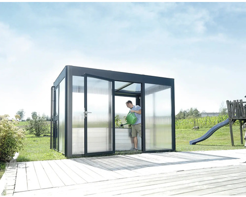Serre avec vitrage transparent et une personne arrosant des plantes
