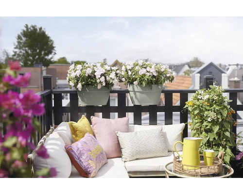 Balcon décoré avec jardinières, coussins et un pichet jaune sur une table