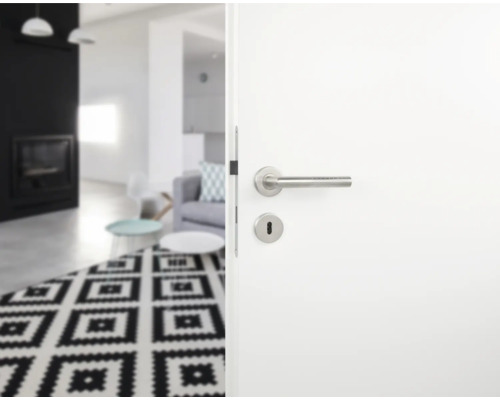 Porte blanche ouverte avec poignée en acier inoxydable donnant sur un salon avec tapis