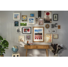 Wand mit diversen Bildern und Dekorationen über einem Holztisch