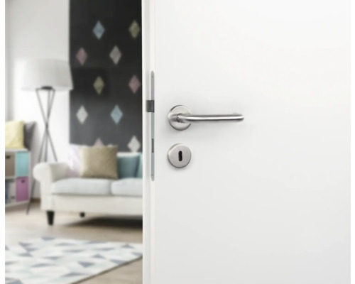 Porte blanche avec poignée de porte argentée et trou de serrure dans une pièce à vivre