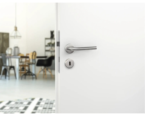 Geöffnete weisse Tür mit silberner Türklinke und Blick in einen hellen Raum
