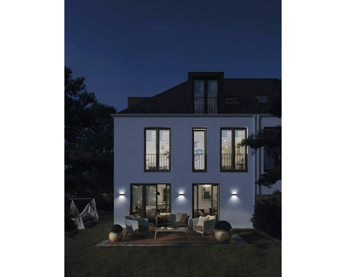 Hausfassade mit Aussenbeleuchtung, Terrasse und Gartenmöbeln bei Nacht