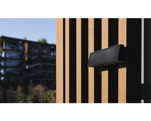 Eine schwarze Aussenwandleuchte an einer Holzfassade.