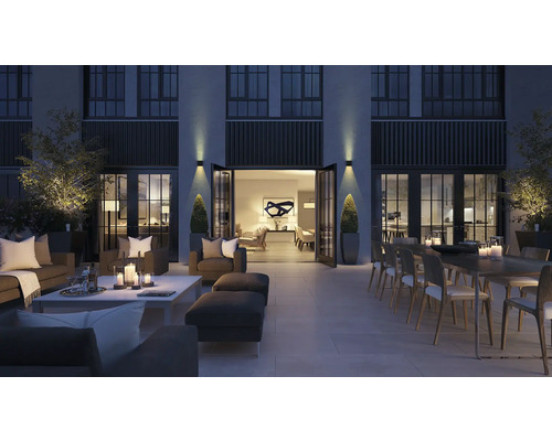 Grosse Terrasse mit Sitzmöbeln, Esstisch und Dekoration bei Nacht.