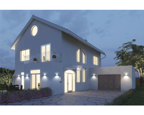 Hausansicht mit Beleuchtung, Garage und gepflasterter Einfahrt bei Nacht