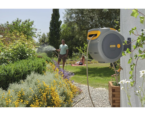 Dévidoir mural dans le jardin avec la famille arrosant les plantes