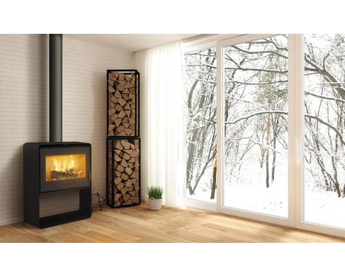 Salon avec poêle à bois, étagère à bois et vue sur les arbres enneigés