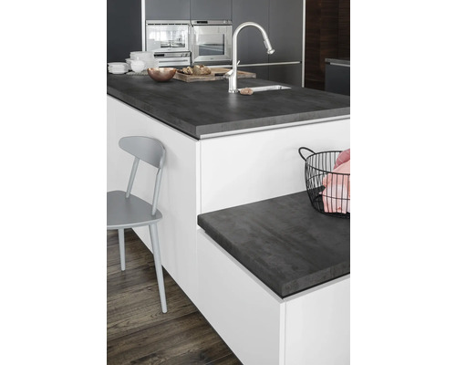Îlot de cuisine avec plan de travail foncé, évier et robinet dans une cuisine moderne.