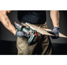 Une personne utilise une cisaille à tôle sans fil Metabo pour couper une pièce.