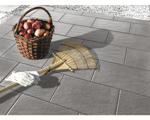 Pavés sur une terrasse avec un panier de pommes, un râteau et des gants de jardin