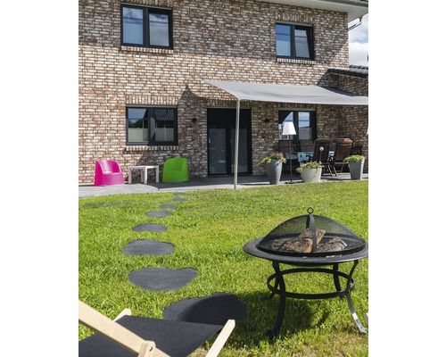 Espace extérieur avec foyer, chaise longue, dalles de chemin et protection solaire devant une maison d''habitation