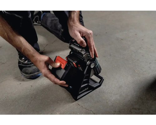 Projecteur de chantier sans fil avec une main insérant la batterie