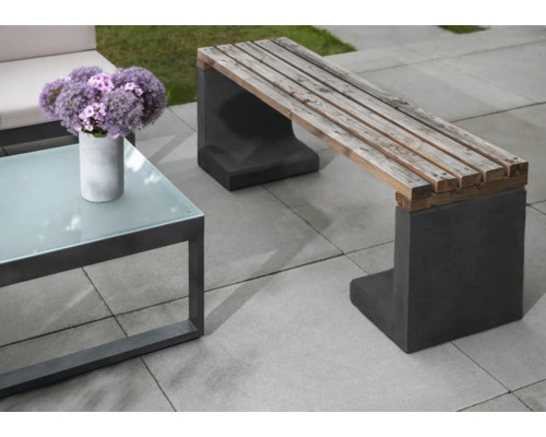 Scène de jardin avec banc en bois sur pieds en béton et une table avec plateau en verre