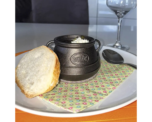 Gusseisen Topf mit Suppe und Brot auf einem Teller