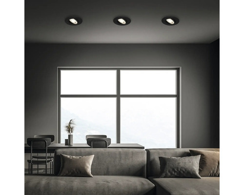 Wohnzimmer mit Sofa, Esstisch, großem Fenster und drei Deckenleuchten