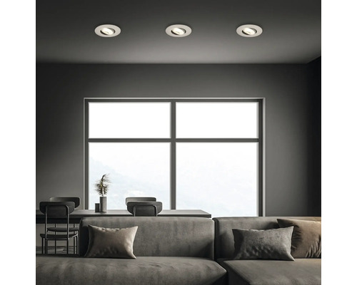 Wohnzimmer mit Sofa, Tisch und drei Deckeneinbauspots zur Beleuchtung