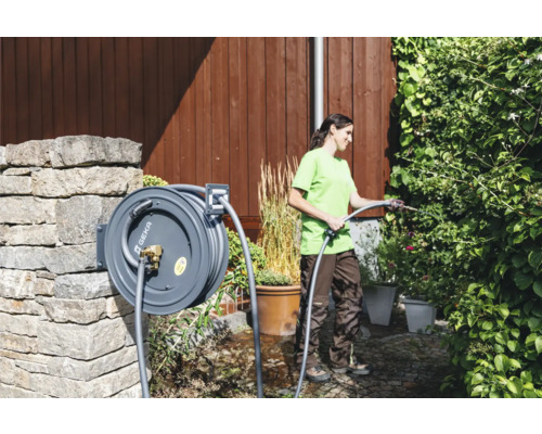 Femme arrose des plantes avec un enrouleur de tuyau de Geka dans le jardin