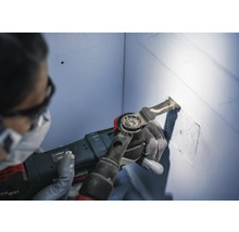 Une personne utilise un outil multifonction pour découper une cavité dans un mur.